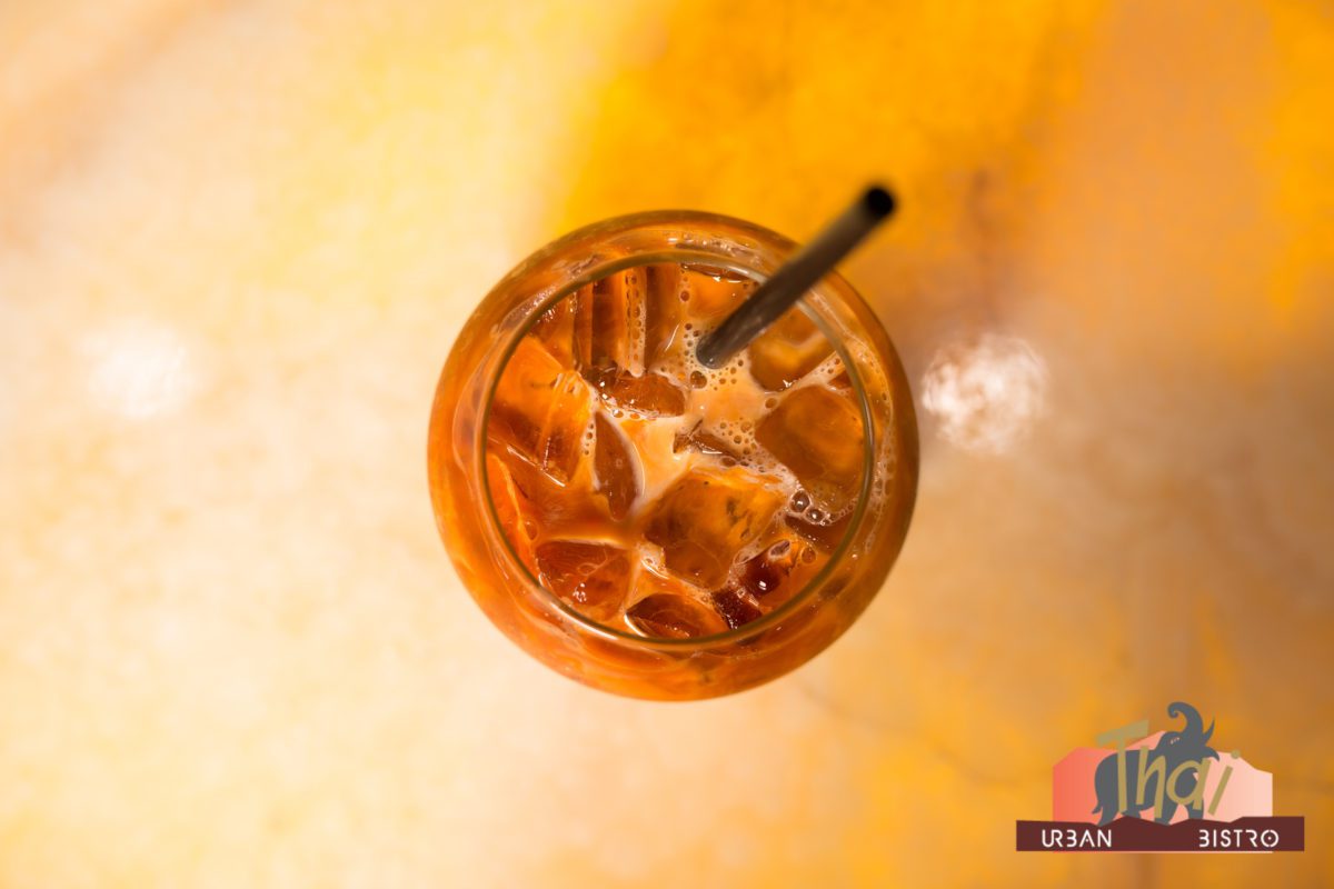 Iced Thai tea in glass with straw.